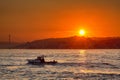 A small boat floats on the sea against the backdrop of the rising sun. Royalty Free Stock Photo